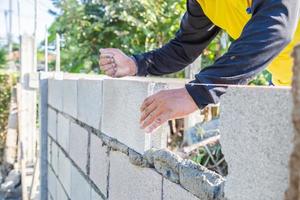 le murature dei lavoratori stanno costruendo muri con blocchi di cemento e malta. foto
