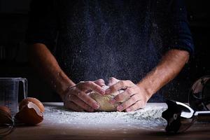 mani maschili che producono pasta per pizza, gnocchi o pane. concetto di cottura. foto