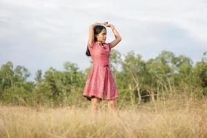 donna asiatica che sorride felicemente alza la mano sullo sfondo della natura del cielo foto