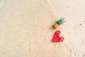 vacanze estive al mare con ananas e infradito in spiaggia foto
