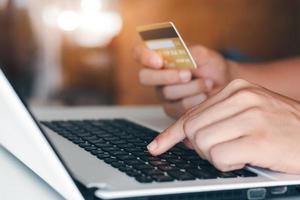 mano dell'uomo d'affari che tiene la carta di credito con l'utilizzo del laptop per lo shopping online mentre si effettuano gli ordini a casa. business, stile di vita, tecnologia, e-commerce, digital banking e concetto di pagamento online. foto