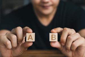 mano maschile che tiene un cubo di legno con entrambe le mani lettera aeb, concetto di business. foto