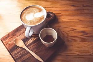 latte caldo in una tazza di caffè bianca su un tavolo di legno. foto
