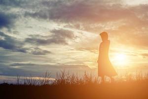 silhouette di donna che prega su sfondo bellissimo cielo foto