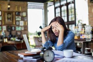 giovane donna seduta in un caffè con il suo laptop, stressante per il lavoro. foto