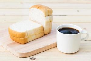 tazza di caffè e pane sul pavimento di legno foto