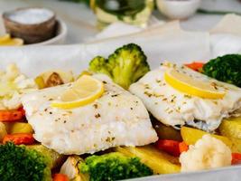 merluzzo di pesce al forno con verdure - dieta sana cibo sano. marmo bianco chiaro foto