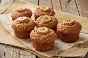 muffin alla banana, vista laterale. cupcakes sul vecchio tovagliolo di lino, tavola in legno rustico, colazione con torta foto