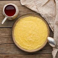 polenta di porridge con tazza di tè, fondo in legno scuro, vista dall'alto foto