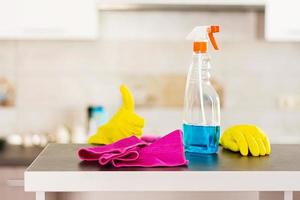 donna in guanti protettivi che puliscono la polvere usando spray detergente e spolverino. concetto di servizio di pulizia. foto