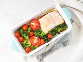 salmone di pesce al forno con verdure - broccoli, pomodori. cibo dietetico sano, sfondo in marmo bianco, vista dall'alto.