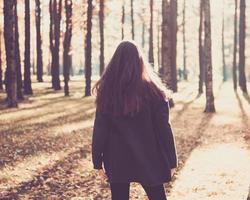 ragazza adolescente in piedi nel parco autunnale con le spalle alla telecamera, si gira sul posto. donna con i capelli lunghi in piedi all'aperto foto