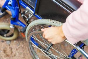 donna con handicap a mano in sedia a rotelle su strada nel parco dell'ospedale in attesa di servizi per i pazienti. ragazza paralizzata irriconoscibile su sedia per invalidi per disabili all'aperto. concetto di riabilitazione. foto