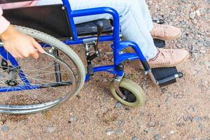 gambe piedi donna con handicap in sedia a rotelle su strada nel parco dell'ospedale in attesa di servizi per il paziente. ragazza paralizzata irriconoscibile su sedia per invalidi per disabili all'aperto. concetto di riabilitazione. foto