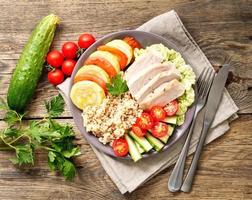 pranzo sano in ciotola di buddha vegetale con tacchino, verdure e quinoa sul dorso di legno marrone foto