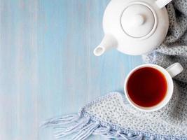 tè, teiera, copia spazio, calda sciarpa lavorata a maglia su sfondo di legno blu, casa accogliente, vista dall'alto foto