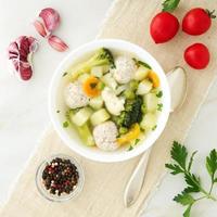 ciotola di zuppa, una tazza di brodo e verdure, polpette di tacchino e pollo, vista dall'alto foto