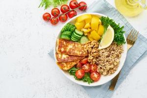 ciotola di buddha con quinoa, halloumi, insalata di lattuga, cucina vegetariana, sfondo bianco, vista dall'alto foto