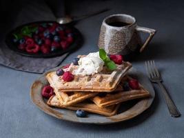 cialde belghe con lamponi, sciroppo di cioccolato. colazione con tè su sfondo scuro, vista laterale foto