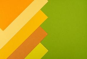 strati di carta di cartone arancione, giallo e verde sovrapposti colorati sullo sfondo foto