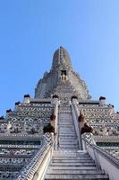 pagoda bianca nel tempio di wat arun e cielo blu. statue antiche intorno alla base della pagoda. wat arun è un antico monumento in Thailandia. foto
