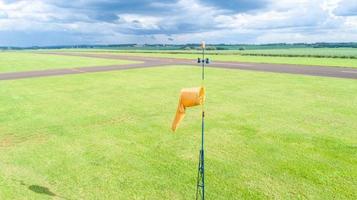 manica a vento arancione manica a vento sull'aerodromo, sfondo piantagione di canna da zucchero. foto