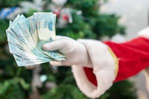 babbo natale che conta banconote brasiliane. note reali. Banconote da 100 reais. concetto di risparmio per la fine dell'anno. spesa durante il natale. speso in regali di natale. foto