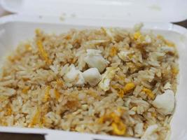 riso fritto con polpa di granchio condito con uova strapazzate, cibo tailandese in stile in scatola di carta bianca da leggere da mangiare, da portare a casa foto