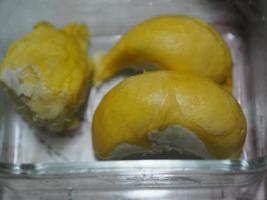 frutto durian con polpa dalla corteccia affilata nel colore giallo dolce in scatola di plastica trasparente foto