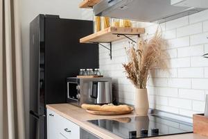 interno della cucina in stile rustico con stoviglie vintage e pareti in legno. mobili bianchi e decorazioni in legno in un luminoso cottage al coperto. foto