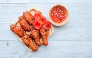 vista dall'alto e primo piano di un'ala di pollo fritta in un piatto bianco con salsa dolce su sfondo di legno. cibo popolare per i bambini. foto