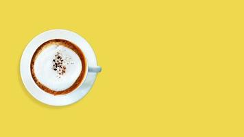 caffè cappuccino vista dall'alto su sfondo giallo.