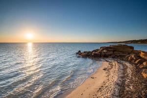 il paesaggio della baia di mezza luna durante il tramonto sulla spiaggia di roccia nera di melbourne, australia. foto