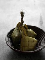 primo piano di ketupat in una ciotola di bambù sul tavolo foto