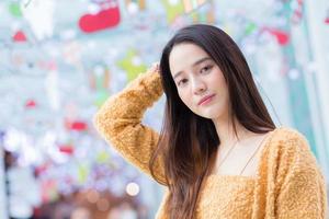 la bella femmina asiatica con i capelli lunghi indossa il cappotto giallo e sorride felicemente. nel tema per festeggiare natale e felice anno nuovo foto