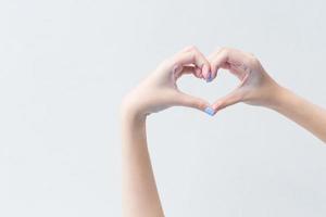 la bella mano femminile mostra il simbolo del cuore come segno di amore nel concetto di manicure. foto