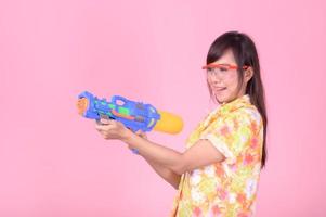 una bella donna asiatica mostra un gesto mentre tiene in mano una pistola ad acqua di plastica durante il festival di Songkran foto