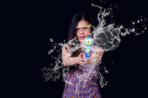 una bella donna asiatica mostra un gesto mentre tiene in mano una pistola ad acqua di plastica durante il festival di Songkran foto