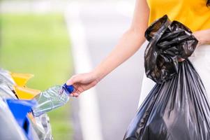 la ragazza ha portato la bottiglia d'acqua di plastica che è stata svuotata dell'acqua, smistata in contenitori preparati per la conservazione per il riciclaggio foto