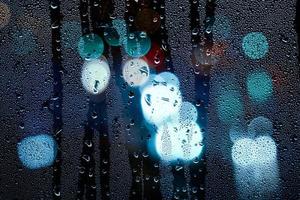 gocce di pioggia sulla finestra e lampioni di notte foto