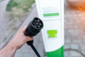 cavo di ricarica in mano presso la stazione di ricarica per veicoli elettrici primo piano foto