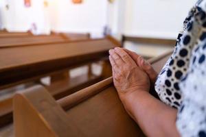 donna anziana che prega in chiesa con le braccia conserte da vicino. foto