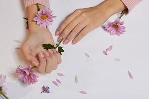 moda arte cura della pelle delle mani e fiori rosa nelle mani delle donne foto