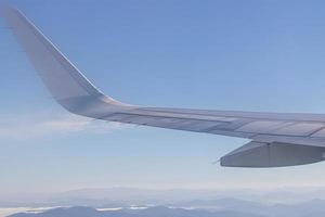 ala dell'aereo con uno splendido skyline di alba. aereo che vola sul cielo blu. vista dalla finestra dell'aeroplano. volo di una compagnia aerea commerciale al mattino con la luce del sole. ala dell'aereo sopra le nuvole. foto