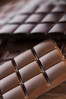 barrette di cioccolato fondente fatte in casa e baccello di cacao su legno foto