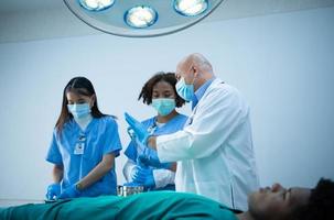 un professore di medicina insegna chirurgia a studenti di medicina che lavorano foto