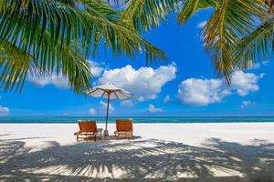 spiaggia tropicale natura come paesaggio estivo con sedie a sdraio e palme e mare calmo per banner spiaggia. lussuoso paesaggio di viaggio, bellissima destinazione per vacanze o vacanze. scena della spiaggia