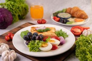 la colazione consiste in pane, uova sode, condimento per insalata di uva nera, pomodori. foto