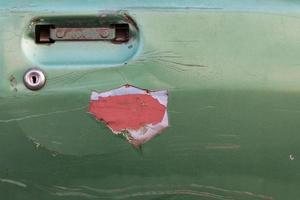 vecchia auto con portiera verde disintegrata. foto