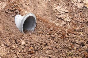 piccolo tubo di cemento sepolto in terreno sabbioso. foto